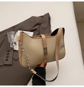 Detail of woven beige texture on shoulder bag with silver chain and metal clasp closure