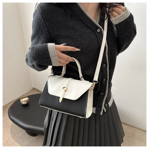 Detail of contrast color crossbody bag with white patent leather flap and gold hardware