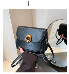 Detail view of black vintage oil wax leather saddle bag with gold U-shaped metal buckle