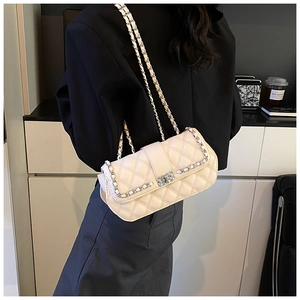 Close-up of off-white quilted chain bag with silver lock worn by a model
