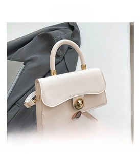 Détail du sac à main en cuir crème avec fermoir rotatif doré et poignée circulaire