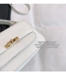 Detail of white leather handbag featuring a golden turn-lock closure and fine stitching