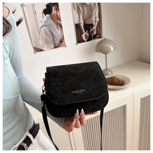 Detail of black pleated saddle bag with Fashion Trend Est 1996 text held in hand