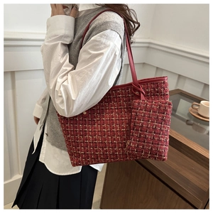 Detail of red tweed plaid tote bag and matching pouch on model in minimal room