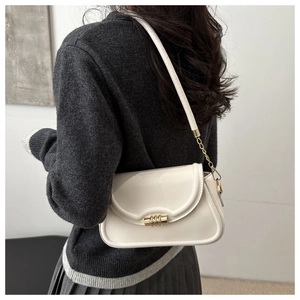 Close-up of cream crossbody square bag with gold metal clasp and chain strap detail