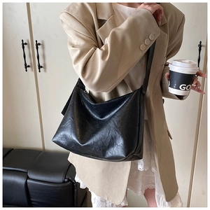 Détail d'un grand sac bandoulière vintage noir montrant la texture du cuir PU et la sangle