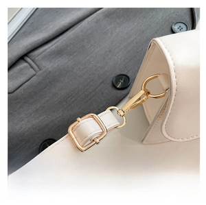 Détail macro de la bandoulière réglable avec garnitures dorées sur un sac à main blanc