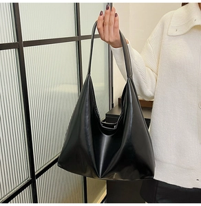 Détail d'un sac cabas minimaliste en cuir noir tenu par un mannequin en intérieur chic