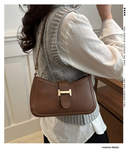 Détail d'un sac hobo marron avec boucle H dorée porté par un mannequin en studio