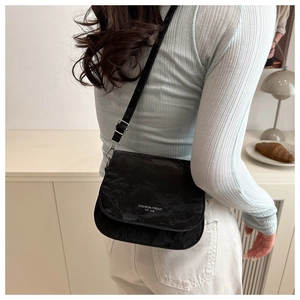 Close-up of black saddle bag with FASHION TREND lettering and adjustable strap