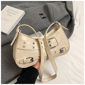Detail of beige Y2K hobo bag with silver metal eyelets and decorative buckles on the side