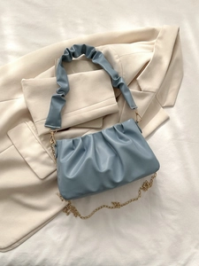 Detail of blue pleated cloud bag featuring soft matte leather and golden chain strap
