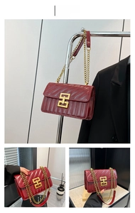 Detail of burgundy quilted crossbody bag with golden square clasp and chain strap