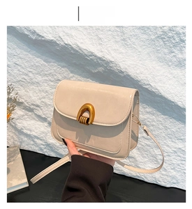 Detail view of cream-white leather crossbody bag with iconic gold horseshoe buckle clasp