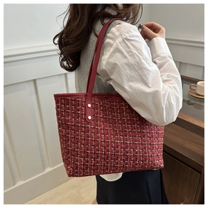 Detail of red tweed tote bag with woven texture and gold rivets on leather straps