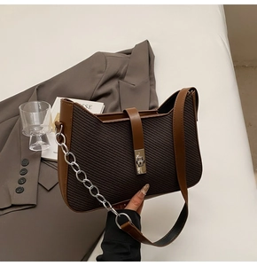 Detail of vintage woven texture on brown shoulder bag with leather strap and metal chain