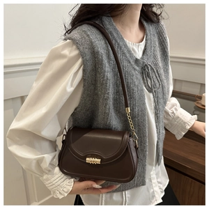 Model view of a dark brown shoulder bag with gold chain details and textured hardware