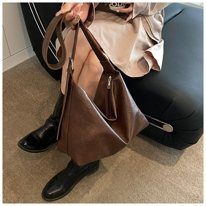Détail d'un sac bandoulière en cuir texturé marron foncé avec fermeture éclair argentée