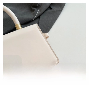 Détail du sac à main en cuir crème avec finitions dorées et coutures précises