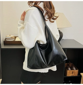 Gros plan d'un grand sac hobo noir minimaliste à l'aspect brillant sur un mannequin