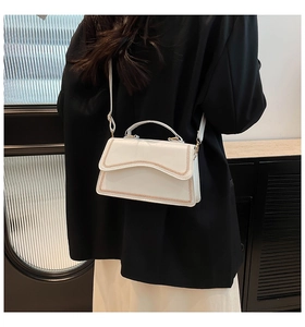 Detail of white rectangle bag featuring wave-edged flap and brown contrast stitching