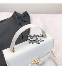 Detail view of white leather crossbody bag with gold twist-lock and top handle