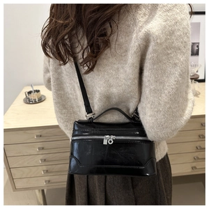 Detail of vintage black shiny leather square bag with dual silver zipper hardware
