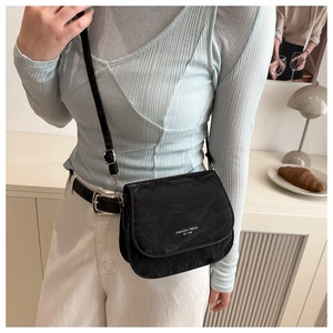 Detail of black nylon saddle bag with 'FASHION TREND' text and adjustable shoulder strap