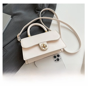 Mini sac carré en cuir blanc crème avec fermoir doré comparé à un téléphone pour la taille