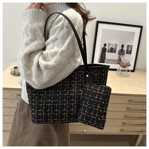 Close-up of a black tweed tote bag with gold thread and matching coin purse on a model