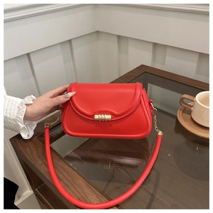 Macro shot of stylish red leather crossbody bag with premium gold cylindrical lock