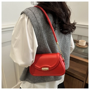 Detail view of the red leather shoulder bag with gold hardware worn by a model