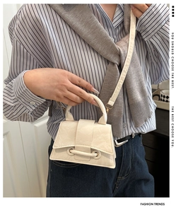 Detail of cream crossbody bag showing horizontal bar clasp and textured faux leather