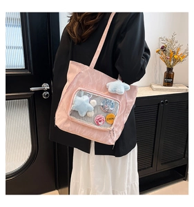 Pink tote bag detail with clear PVC window showing cute badges on a female model
