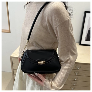Detail of black shoulder bag featuring gold ripple clasp and metal chain strap