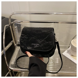 Detail of black saddle bag featuring artistic pleats and thin shoulder strap on a silver cart