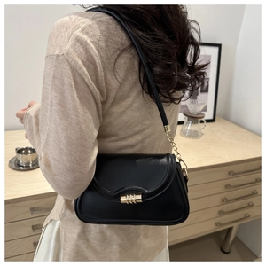 Detail of black faux leather shoulder bag with gold metal twist lock and chain strap
