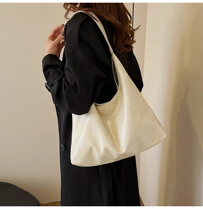 Large cream white leather hobo tote bag shown on model wearing black coat for work