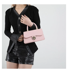Détail d'un sac à main carré rose avec fermoir doré arrondi et poignée supérieure chic