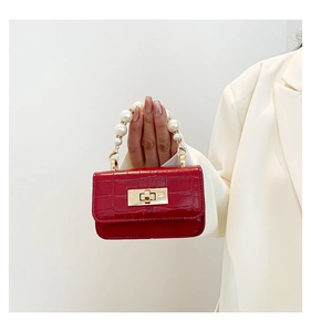 Detail of red croc-embossed leather mini bag with pearl handle and gold clasp closure