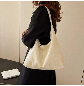 Detail view of cream white crescent tote bag in glossy leather with wide shoulder strap