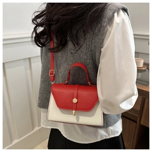 Detail of red and white faux leather crossbody bag with golden buckle on female model
