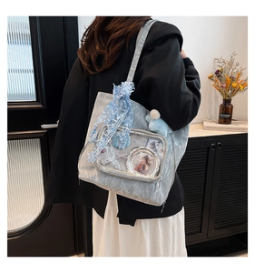 Detail of light blue ita bag with transparent window, lace ribbon and plush ball charm