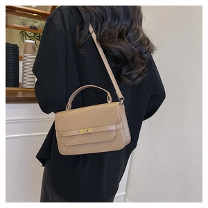 Close-up of beige handbag with gold twist lock on a minimalist indoor scene background