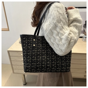 Detail of tweed tote bag with gold thread weave and leather handles on model shoulder