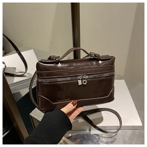 Détail du petit sac carré marron foncé brillant avec ferrures argentées polies