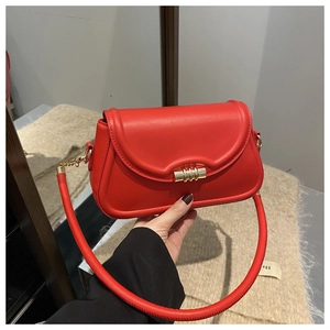 Detail of red leather shoulder bag with circular gold twist lock and sleek curved flap