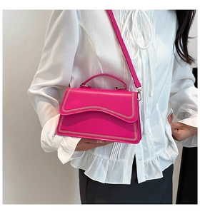 Detail of fuchsia crossbody bag with V-shaped stitching and ergonomic top handle