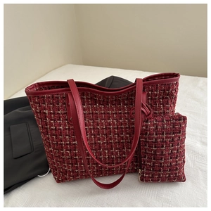 Close-up of red and black tweed tote bag with matching pouch on white bedding