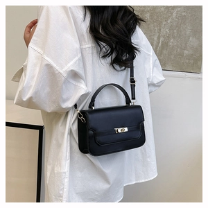 Black leather crossbody bag with silver buckle worn by a model in a white shirt